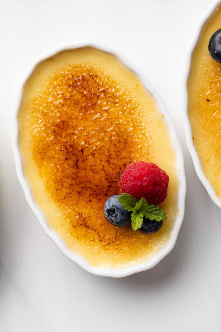 two bowls filled with pudding and berries on top of a table next to each other