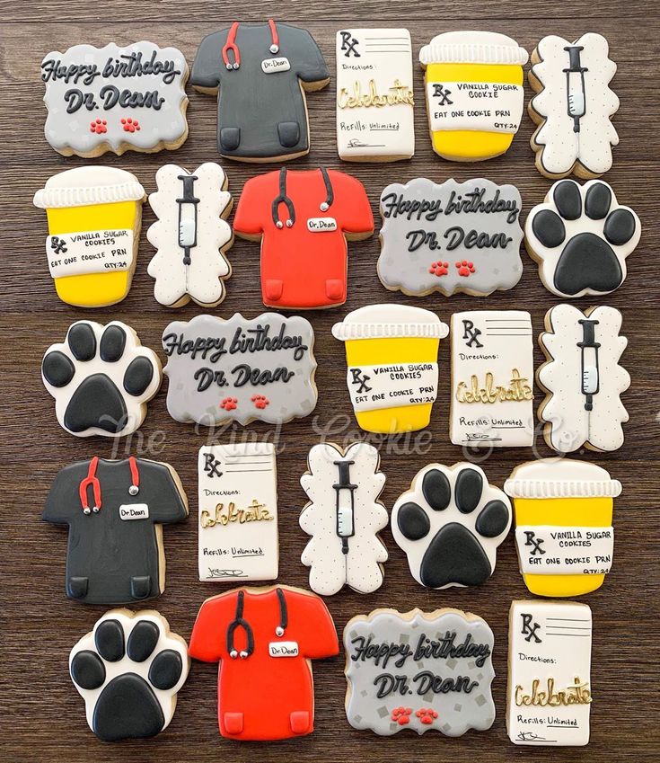 decorated cookies are arranged in the shape of shirts and paw prints on a wooden table