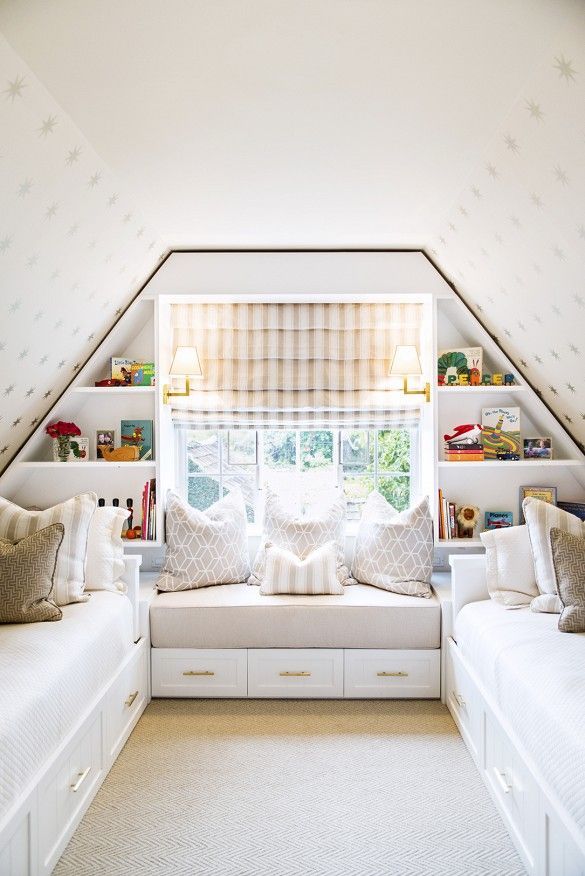 a room with two white couches and some bookshelves on the wall above them