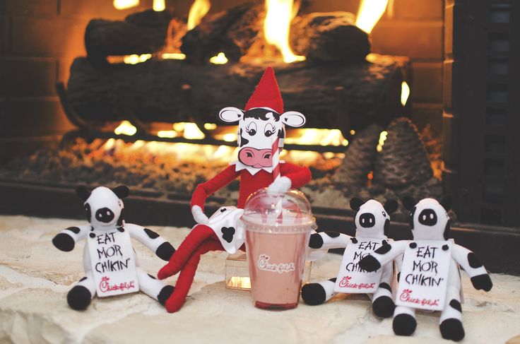 a group of stuffed animals sitting in front of a fire place next to a drink