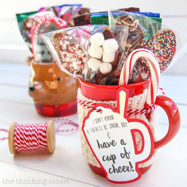 a cup filled with candy and marshmallows next to a spool of twine