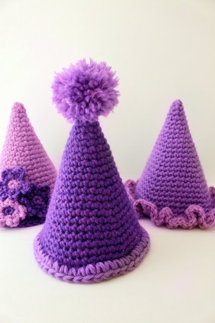 three crocheted party hats with pom - poms on the top and bottom