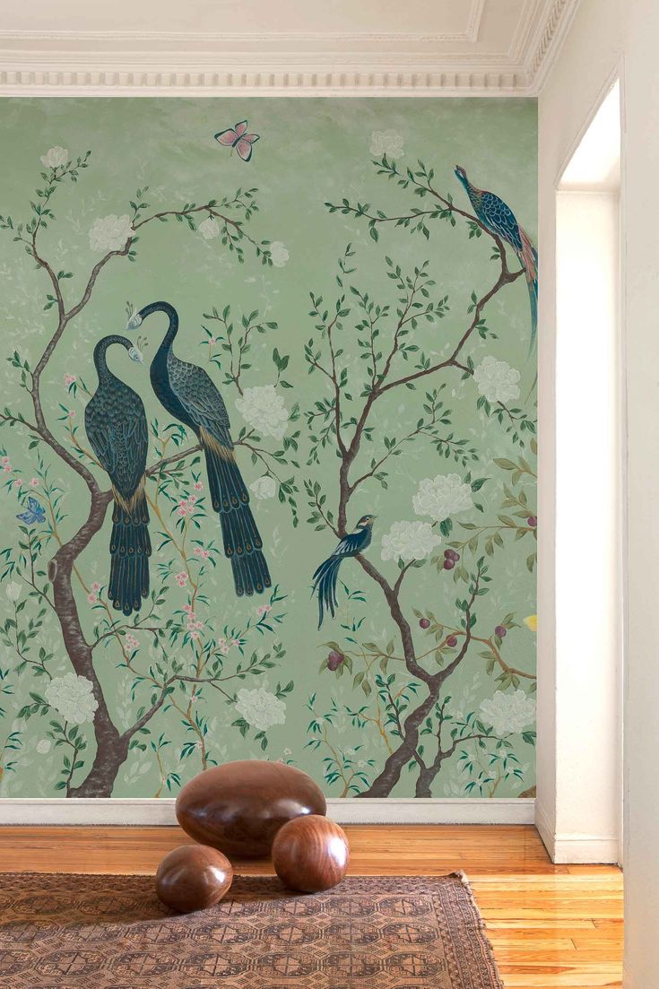 two birds sitting on top of a tree in front of a wallpapered mural