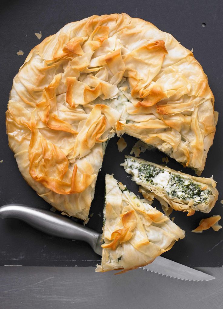 a pie with one slice cut out on a black surface next to a knife and fork