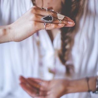 a woman holding out her hand with two rings on it's fingers and wearing a white shirt