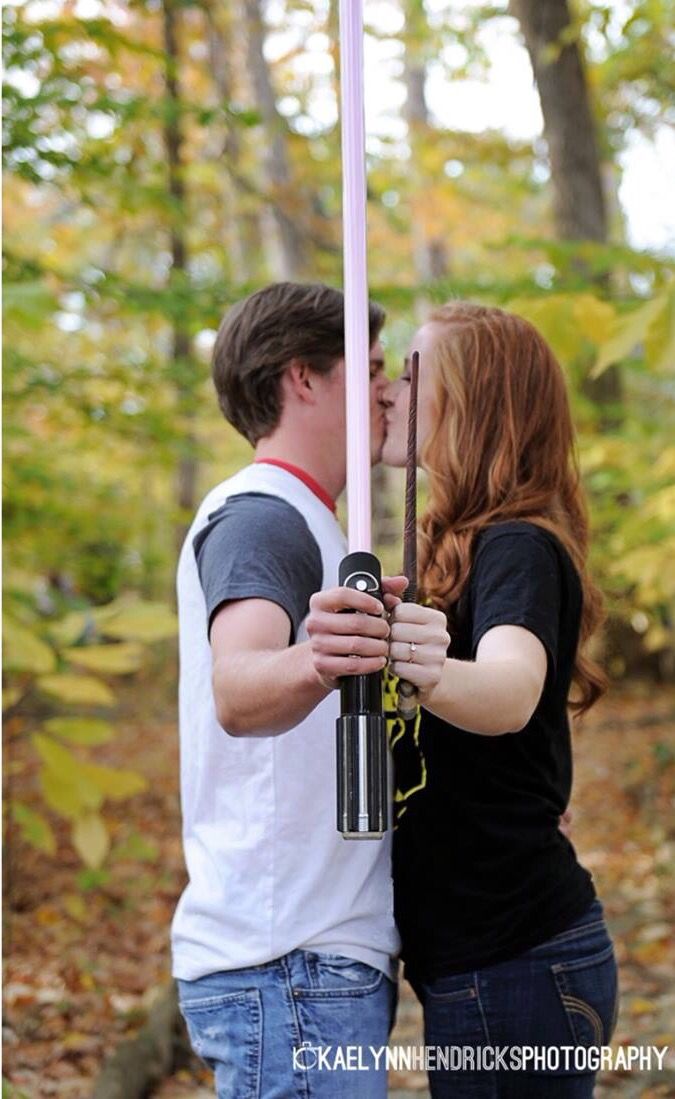 a man and woman standing next to each other in the woods holding onto a pink pole