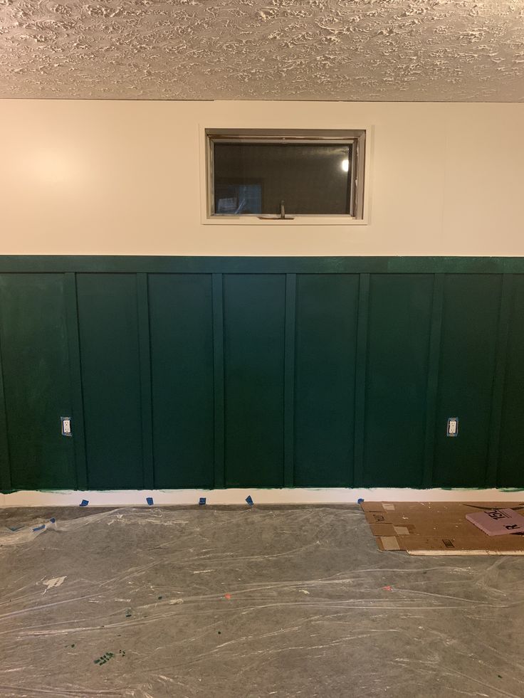 an empty room with green painted walls and a window in the wall that is missing