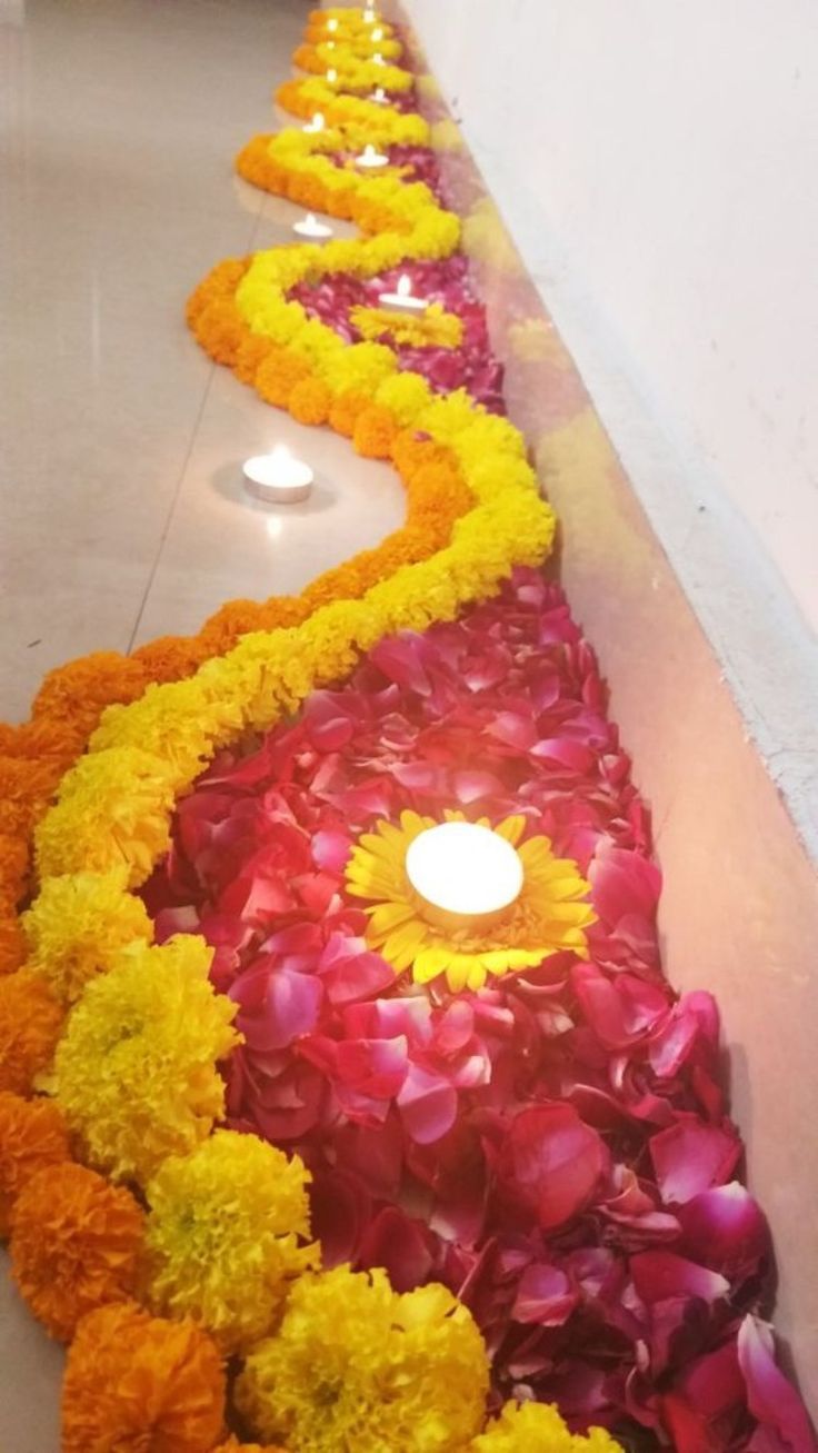 flowers lined up along the side of a wall with a lit candle in between them