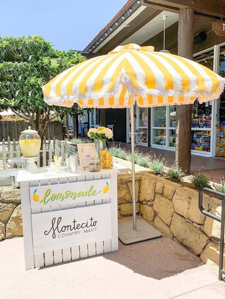 a lemonade stand with yellow and white striped umbrellas