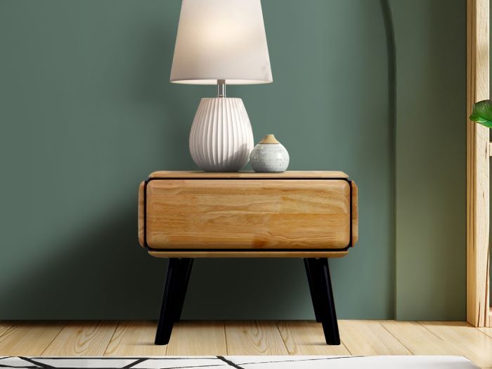 a white lamp sitting on top of a wooden table next to a green painted wall