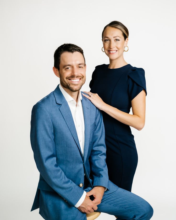 a man in a blue suit and woman in a black dress pose for the camera