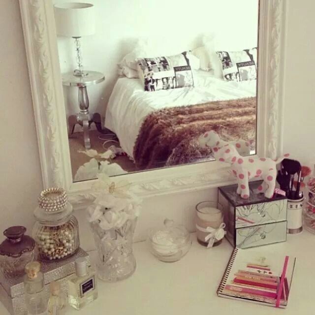 a bedroom with a large mirror and various items on the dresser next to each other