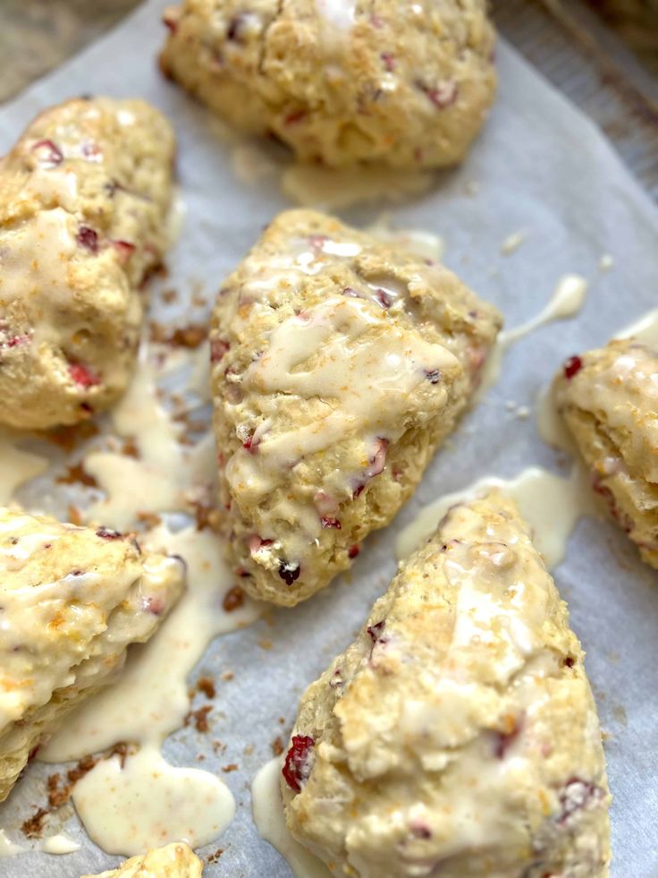 scones covered in icing and cranberries on a sheet of parchment paper