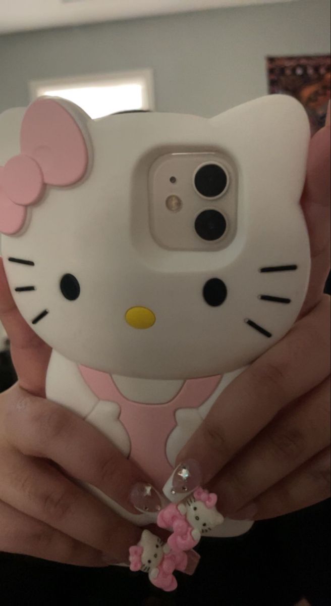 a person holding up a cell phone case with a hello kitty on it