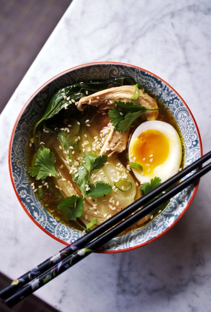 a bowl filled with soup and chopsticks on top of a marble countertop