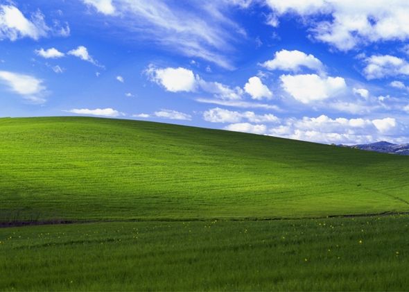 the windows xp wallpaper has been changed to be green and blue with clouds in the background