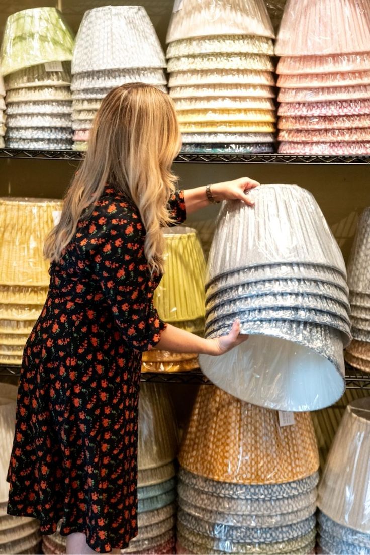 Multiple stacks of fermoie lampshades on shelves in different colors such as blue, green, yellow, and red. Fabric Covered Lampshades, Fermoie Lampshade, Gathered Lampshade, Custom Shades, Creative Display, Georgian Homes, Fabric Lampshade, White Lamp, Chandelier Lamp