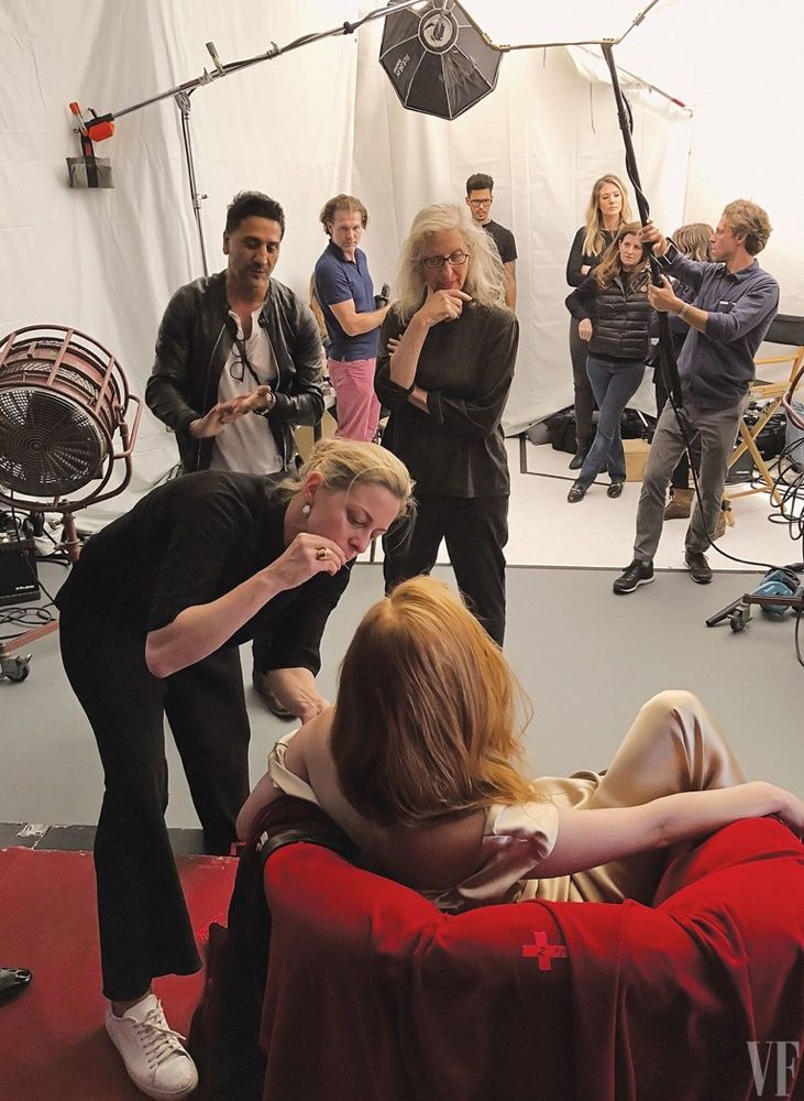 a group of people in a studio with one woman covering her face and the other man holding an umbrella