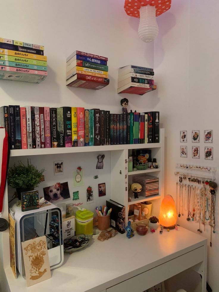 a white desk topped with lots of books next to a wall mounted shelf filled with books