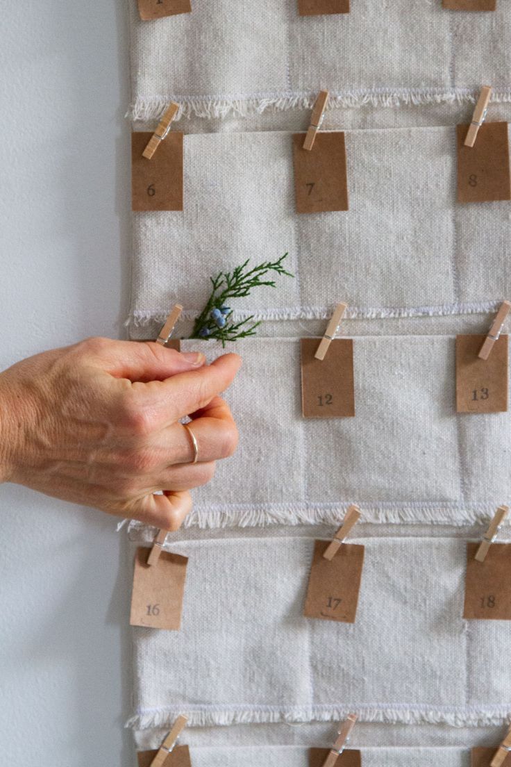 a hand holding a piece of paper with clothes pins attached to it and pinned to a wall