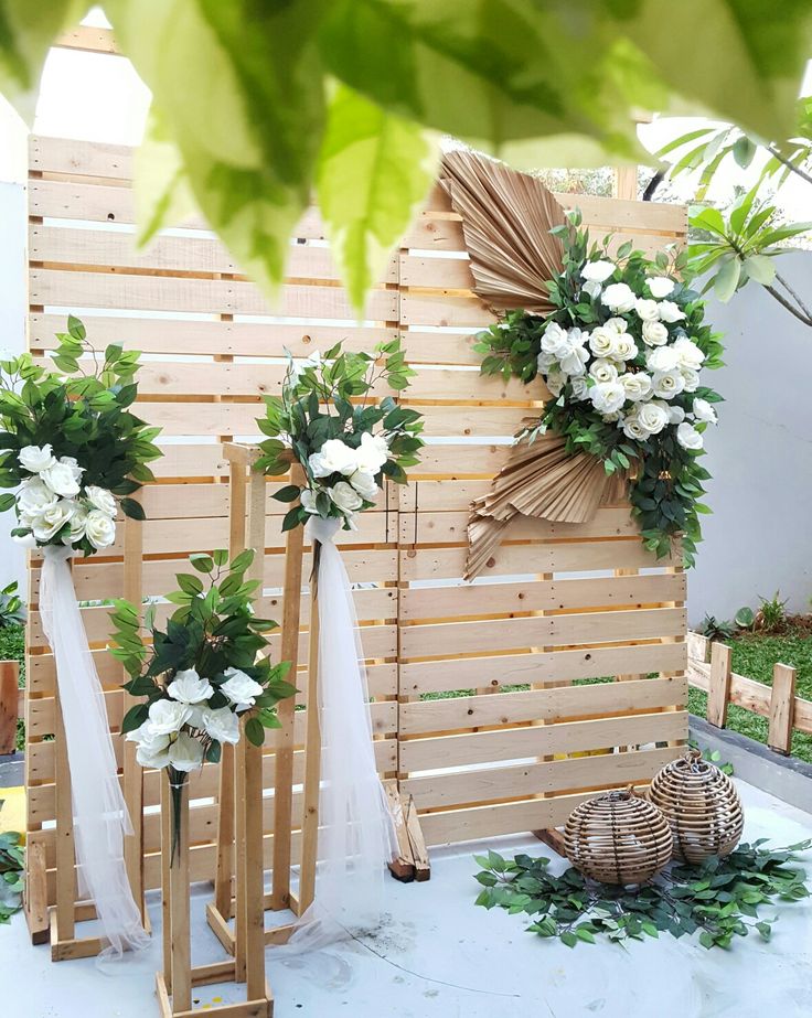 three wooden stands with white flowers and greenery on them in front of a fence