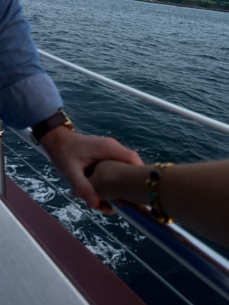 two people holding hands while on a boat