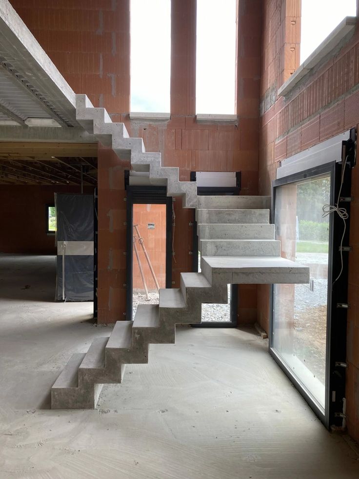 an empty building with concrete stairs and windows in the center, leading to another room