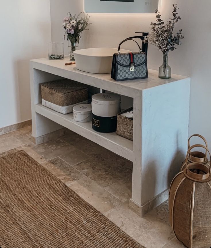 a white sink sitting on top of a wooden counter next to a vase filled with flowers