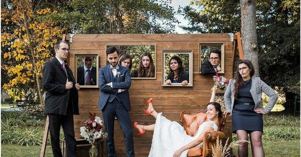 a group of people that are standing in front of a wooden structure with pictures on it