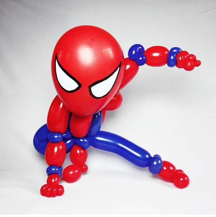 an inflatable spider man sitting on top of a white table next to a red and blue balloon