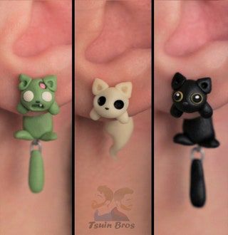 three different types of earrings on someone's left ear, one with a cat and the other with a dog