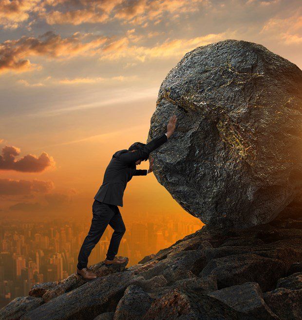 a man pushing a giant rock up into the air with his hands on top of it