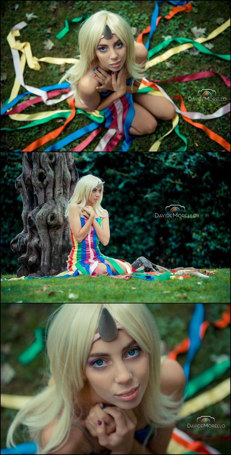 a woman sitting on top of a lush green field next to a tree and colorful streamers