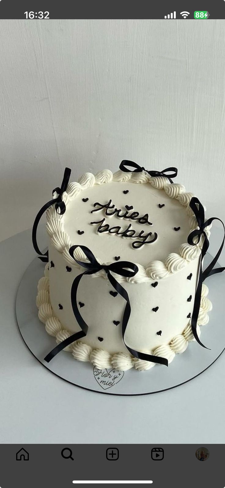 a white cake with black ribbon and bow on top