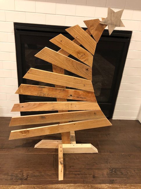 a wooden christmas tree sitting on top of a hard wood floor next to a fireplace