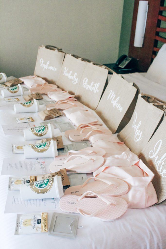 many pairs of pink slippers are lined up on a white bed with matching pillows