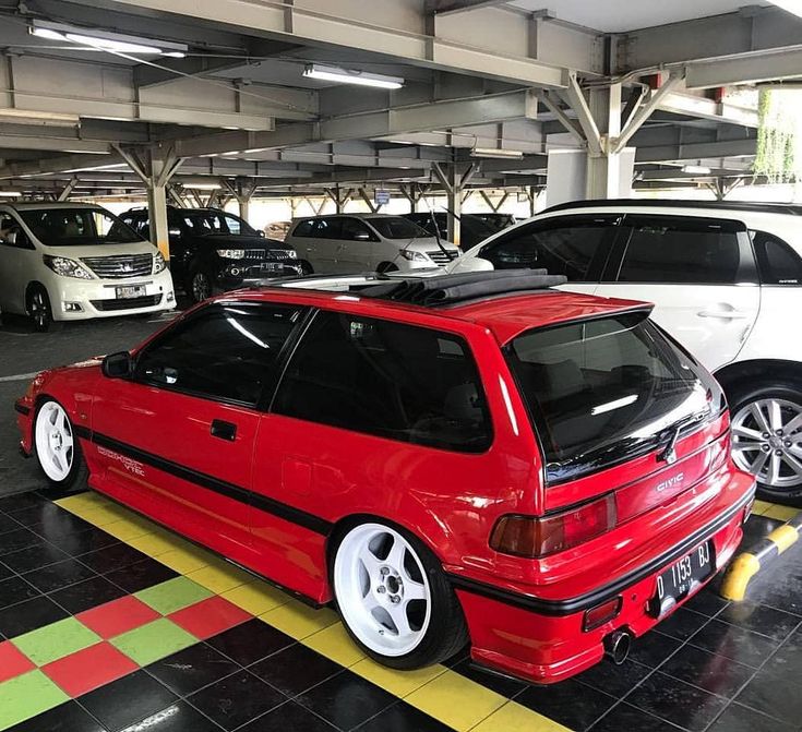 two cars parked in a parking garage next to each other with their hoods down