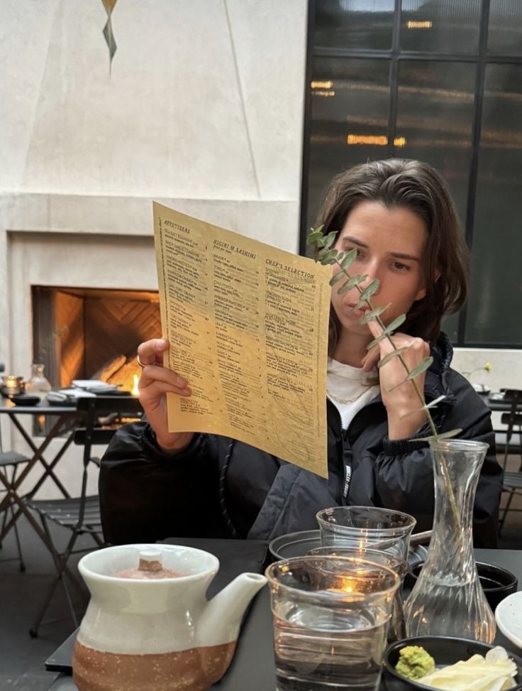 a woman sitting at a table holding up a piece of paper with writing on it