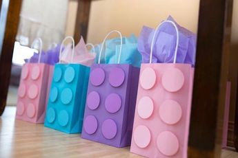 colorful bags are lined up on the floor in front of a mirror, with one bag made out of legos