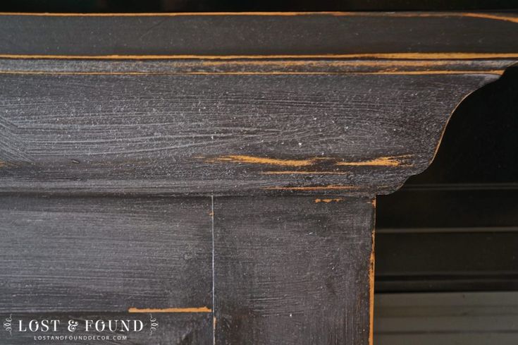 an old black painted wooden shelf with rusted paint on the top and bottom part