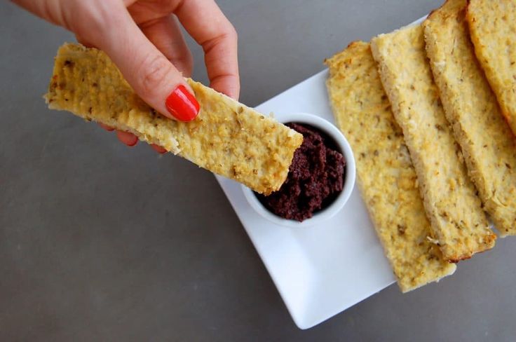 a person dipping something into a small bowl with some sort of cracker on it