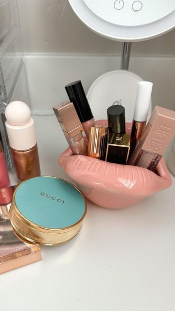 the contents of a makeup set in a pink container on a white counter next to a mirror