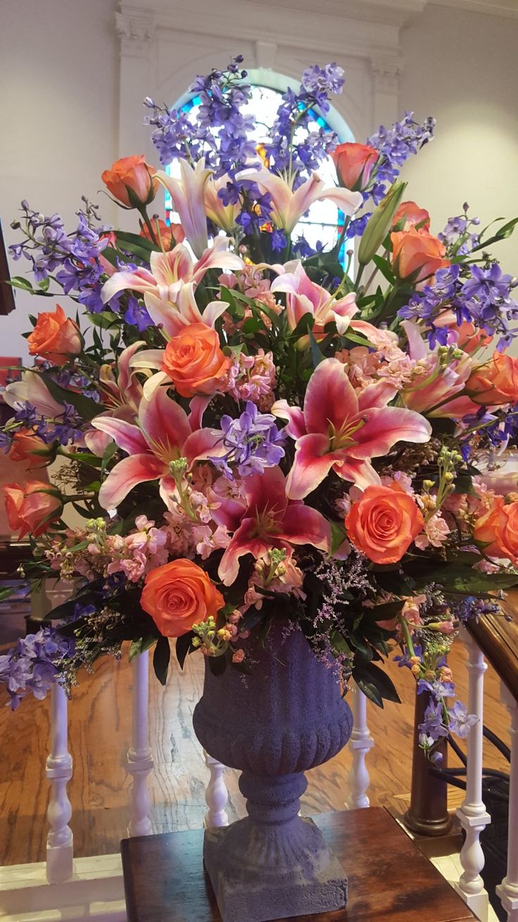 a blue vase filled with lots of flowers on top of a wooden table next to stairs