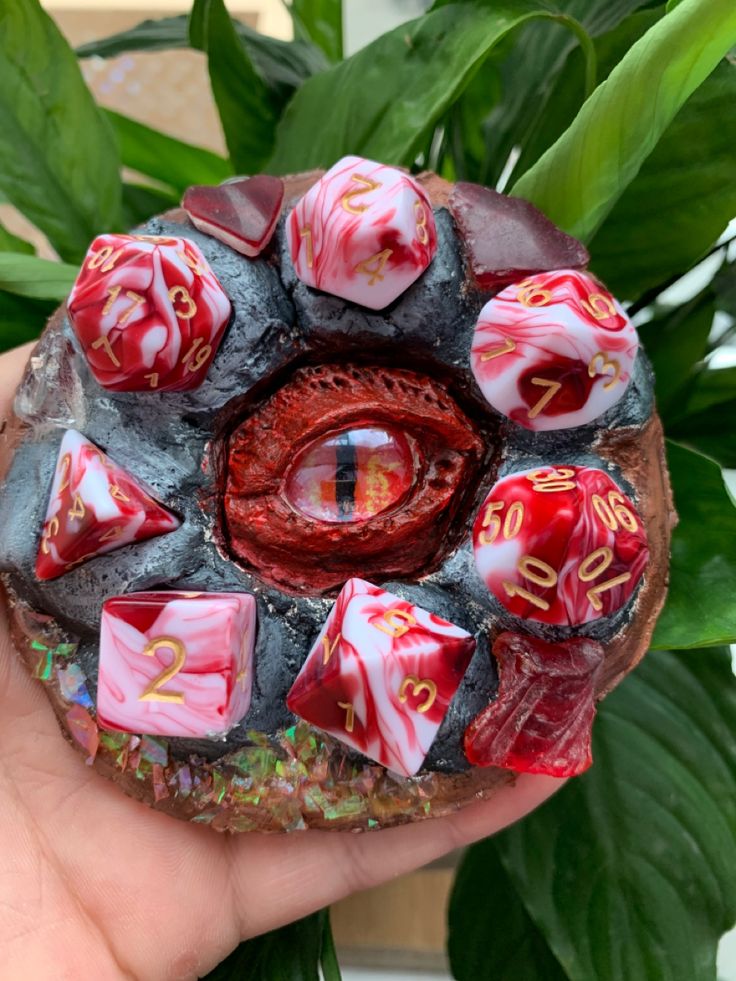 a close up of a person's hand holding a rock with red and white decorations