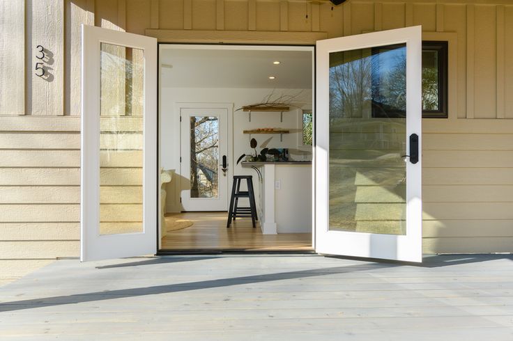 an open door leading into a kitchen and living room area with stools on the floor