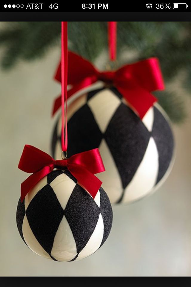 two black and white ornaments hanging from a christmas tree with red ribbon on it's ends