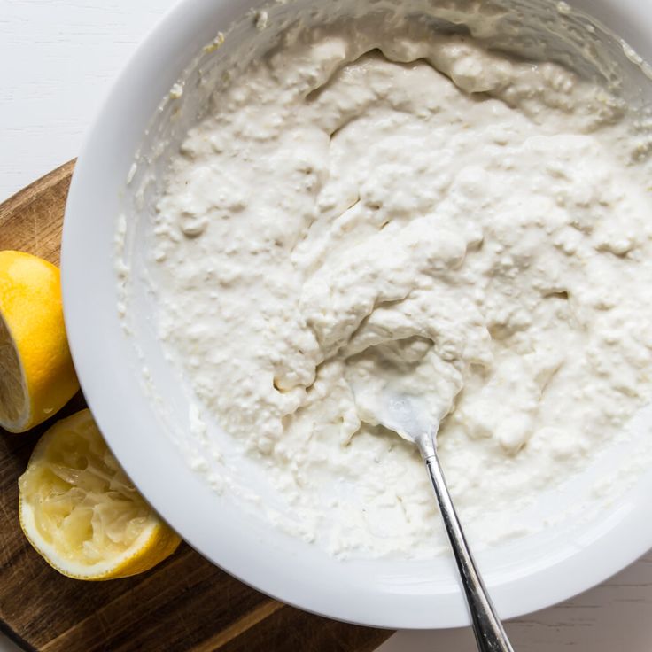 a white bowl filled with sour cream next to sliced lemons