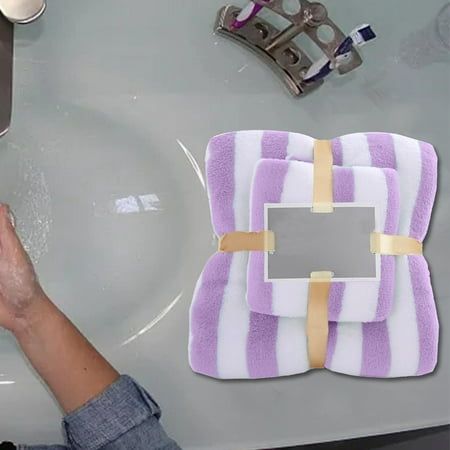 a person is washing their hands in a sink with purple and white towels on it