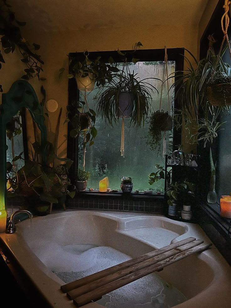 a bath tub sitting next to a window filled with candles and potted plants in front of it