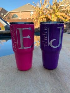 two purple and pink tumblers sitting on top of a table next to a pool